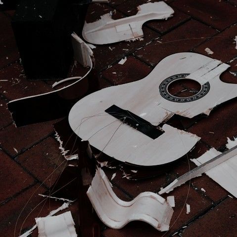 A broken ukulele, shattered in pieces across a wooden floor.